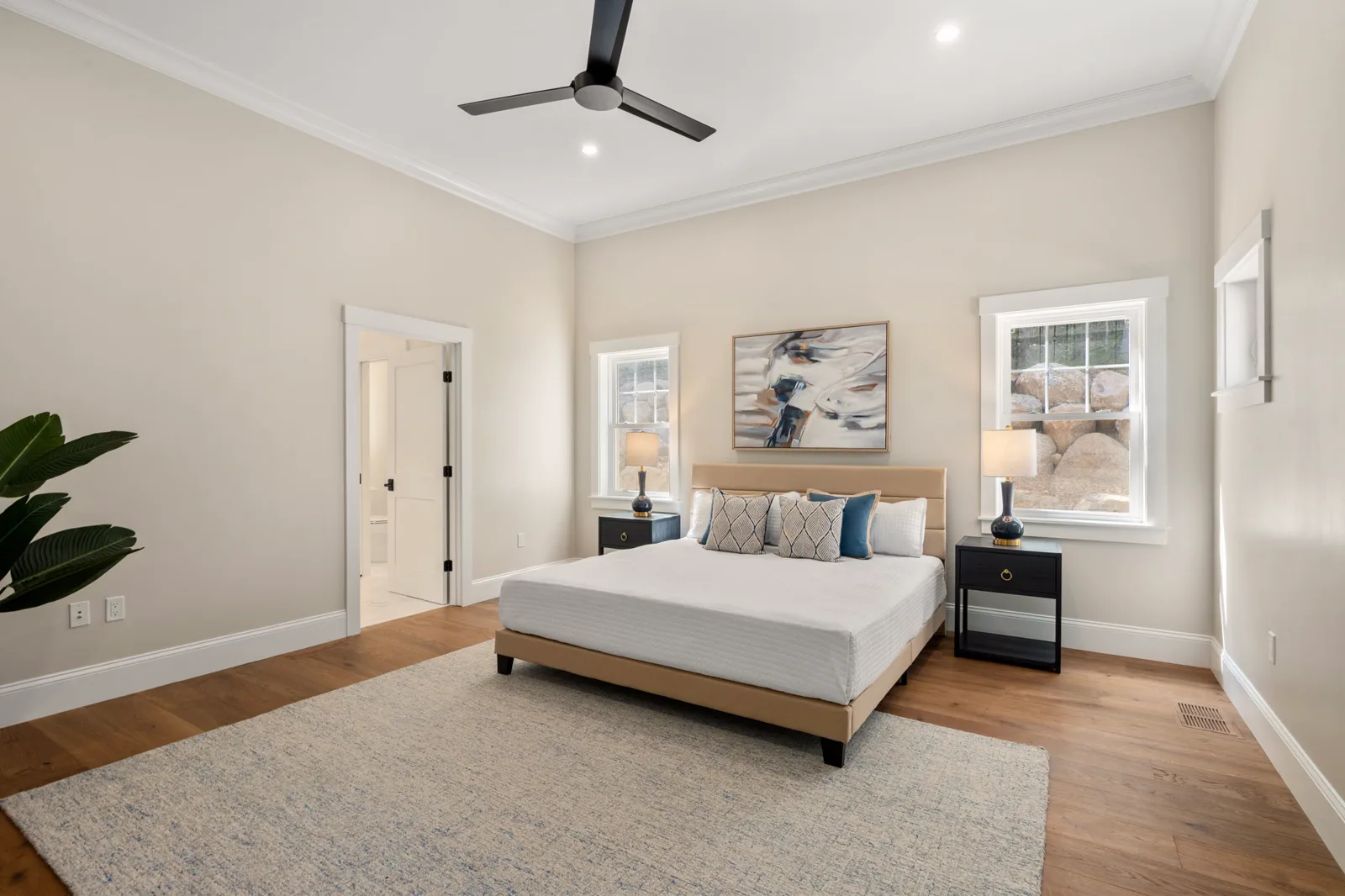 First-floor primary bedroom with ceiling fan and two windows